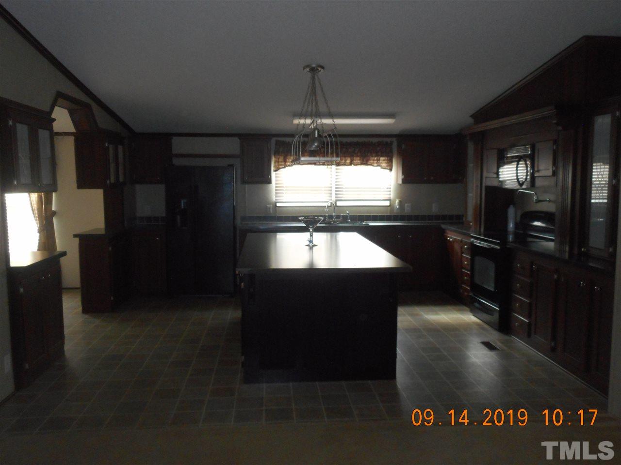 1335 Thomas Store Road Timberlake, NC 27583 - Photo 12 of 13 a kitchen with stainless steel appliances kitchen island granite countertop a refrigerator a stove and a sink