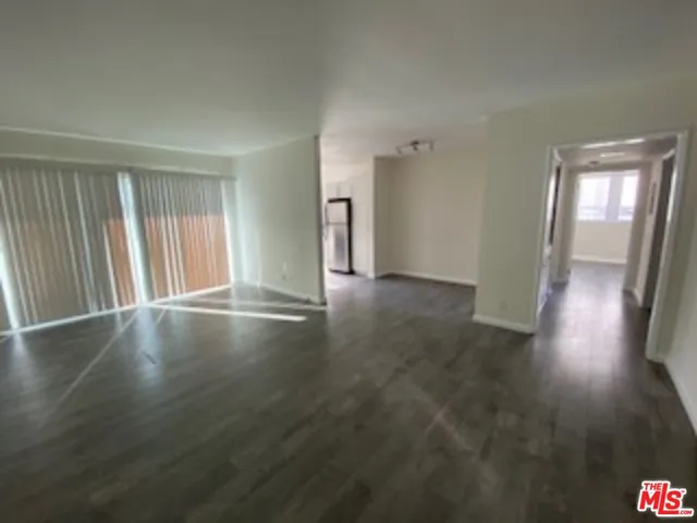 a view of a kitchen with refrigerator and wooden floor