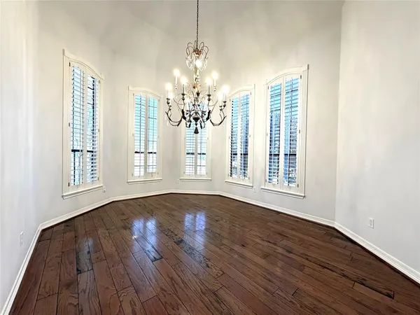 a view of a room with wooden floors chandelier and windows