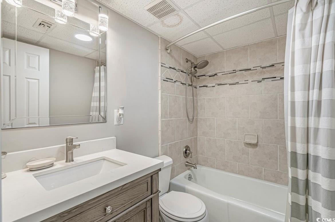 601 Mitchell Drive, Unit 1103 Myrtle Beach, SC 29577 - Photo 15 of 25 Bathroom featuring shower / tub combo with curtain, a drop ceiling, and vanity