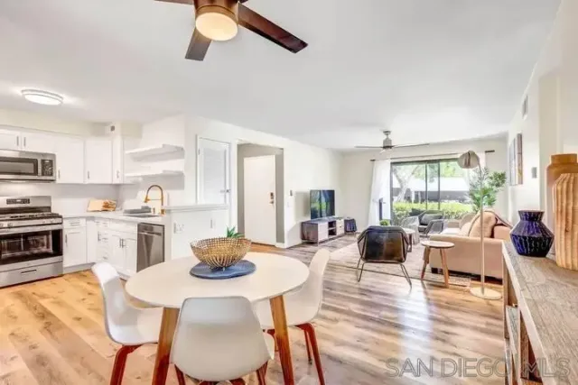 a kitchen with stainless steel appliances kitchen island granite countertop a stove a sink a dining table and chairs with wooden floor