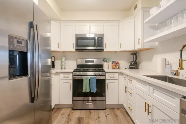 a kitchen with cabinets stainless steel appliances and wooden floor