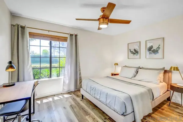 a bedroom with a bed a computer on desk and a window