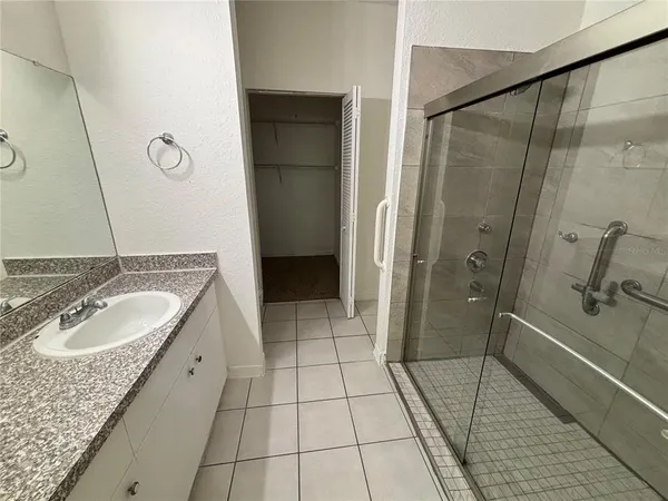 a spacious bathroom with a granite countertop sink a mirror and shower