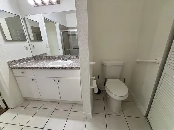 a bathroom with a granite countertop sink a toilet and a mirror