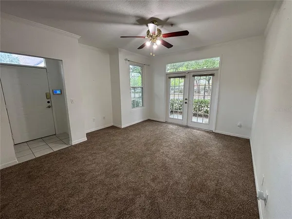 an empty room with windows and ceiling fan