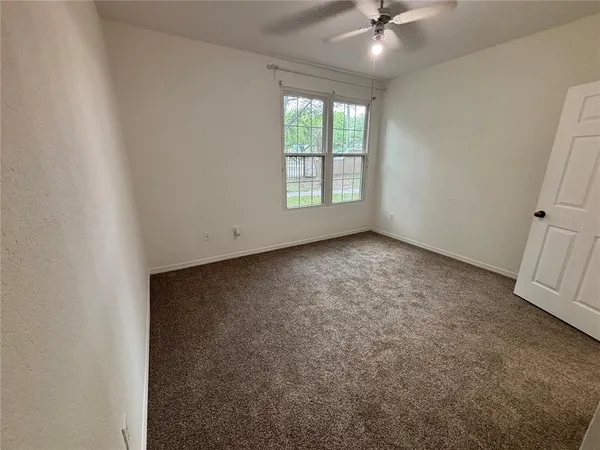 an empty room with a ceiling fan and window