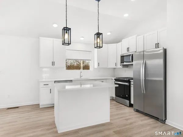 a kitchen with stainless steel appliances granite countertop a sink a stove a refrigerator and island with wooden floor