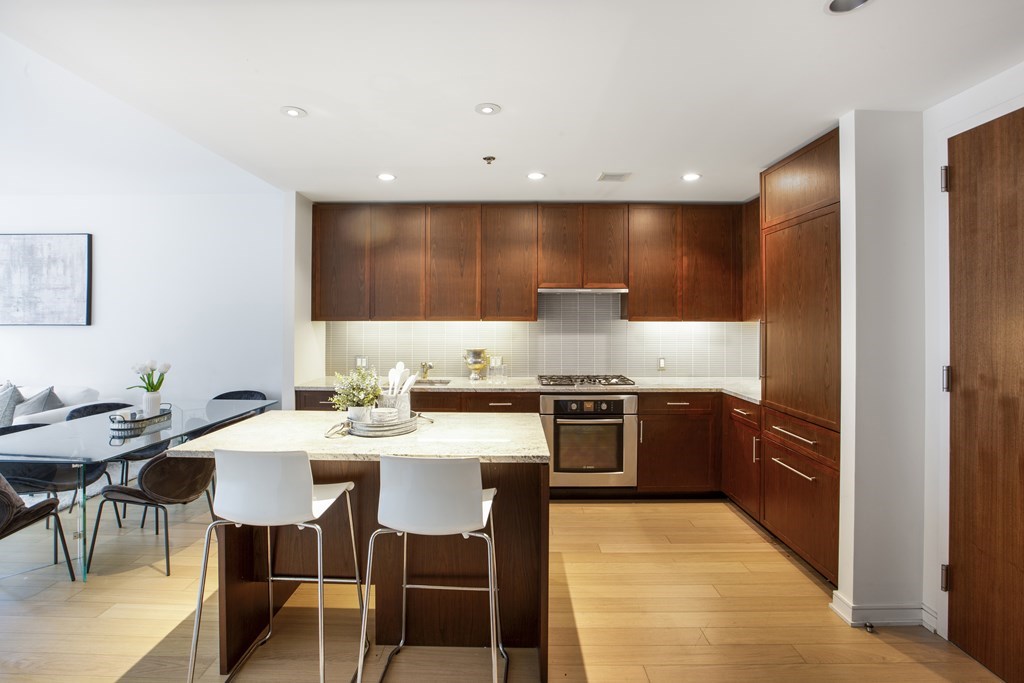 580 Washington Street, Unit 404 Boston, MA 02111 - Photo 11 of 34 a large kitchen with granite countertop a stove a sink a dining table and chairs