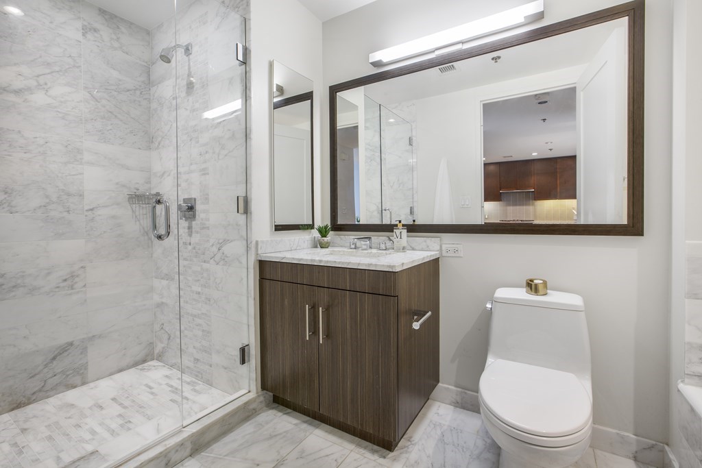 580 Washington Street, Unit 404 Boston, MA 02111 - Photo 16 of 34 a bathroom with a toilet a sink a shower and mirror