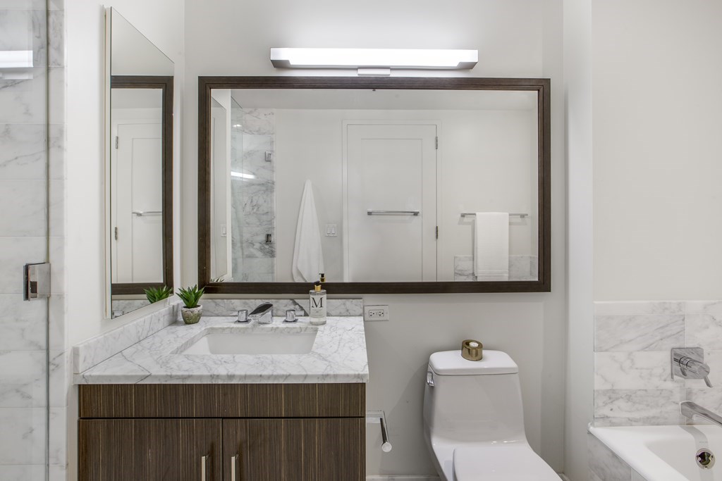 580 Washington Street, Unit 404 Boston, MA 02111 - Photo 17 of 34 a bathroom with a granite countertop sink toilet and mirror