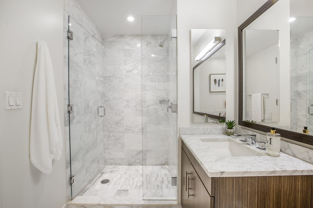580 Washington Street, Unit 404 Boston, MA 02111 - Photo 20 of 34 a bathroom with a granite countertop sink a shower and a mirror