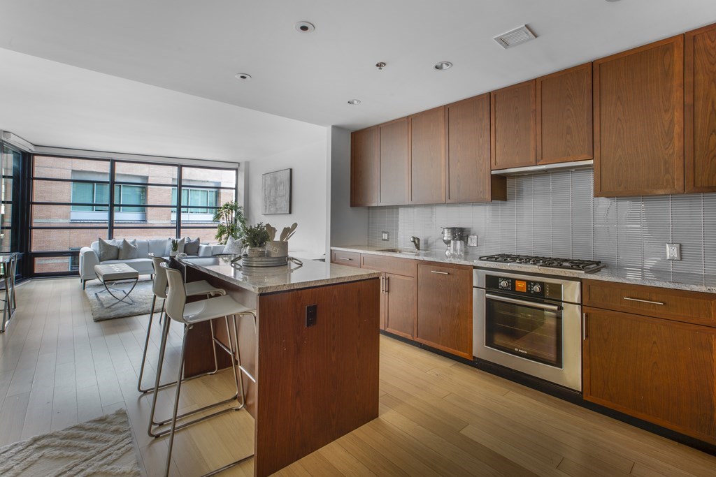 580 Washington Street, Unit 404 Boston, MA 02111 - Photo 9 of 34 a kitchen with stainless steel appliances granite countertop a stove top oven a sink dishwasher and cabinets with wooden floor