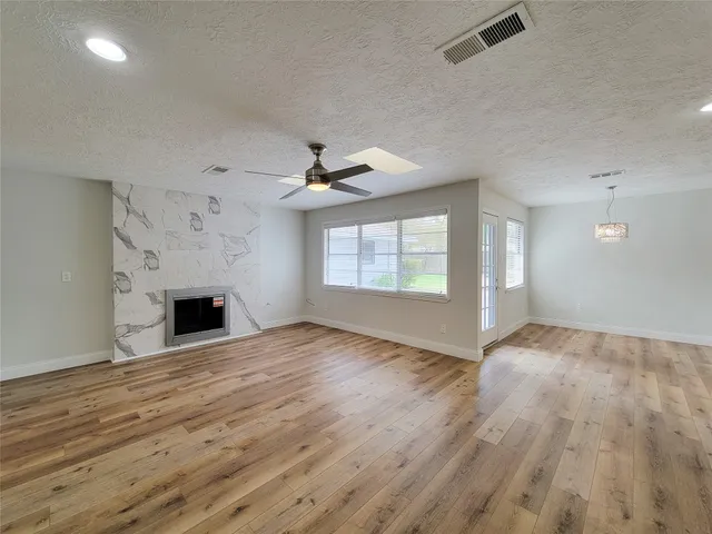an empty room with wooden floor fireplace and windows