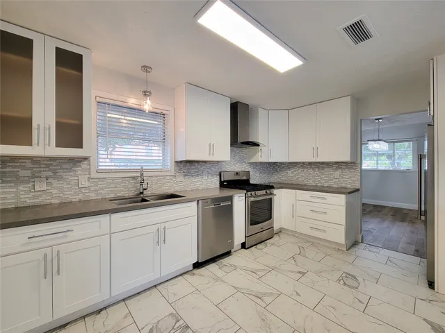 a kitchen with granite countertop white cabinets white appliances a sink and a window