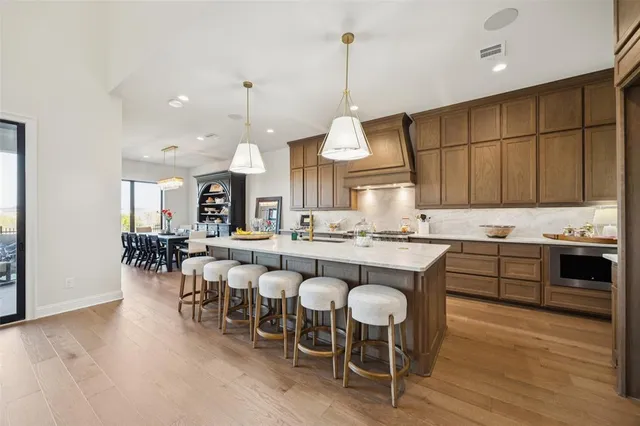 a dining hall with stainless steel appliances granite countertop a stove a kitchen island a dining table and chairs