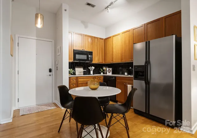 a kitchen with stainless steel appliances a dining table chairs and refrigerator