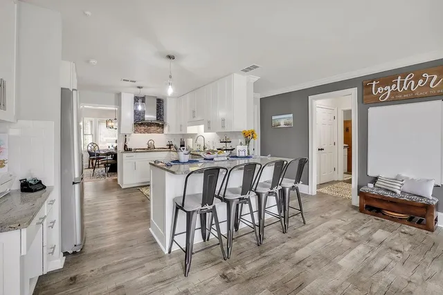 a kitchen with stainless steel appliances a dining table chairs and a refrigerator