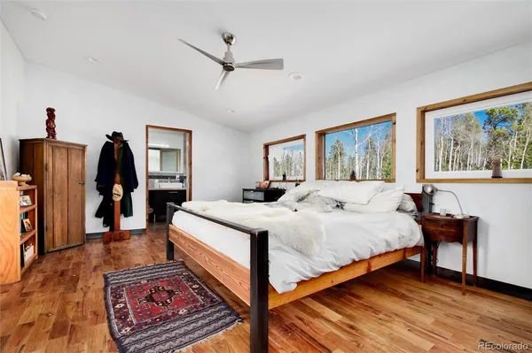 a bedroom with a bed a dresser and wooden floor