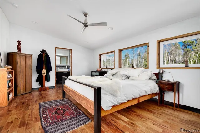 a bedroom with a bed a dresser and wooden floor