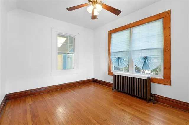 an empty room with wooden floor fan and windows