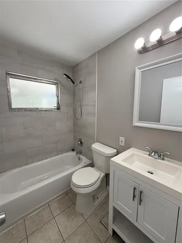a bathroom with a toilet a sink a mirror a bathtub and vanity