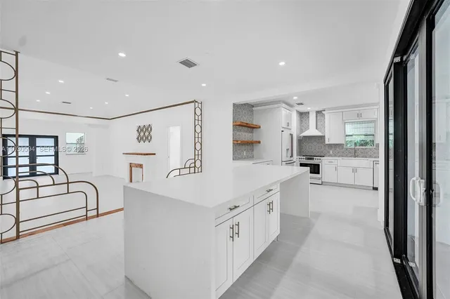 a large white kitchen with stainless steel appliances lots of white cabinets