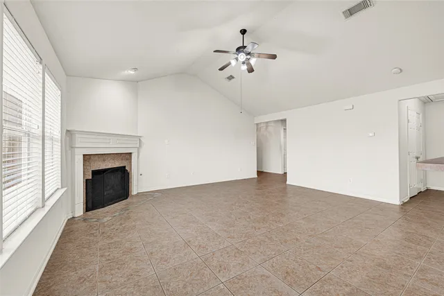 a view of an empty room with chandelier fan and fire place