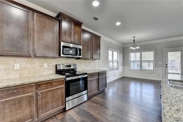 a kitchen with stainless steel appliances granite countertop a sink a stove and a wooden floors