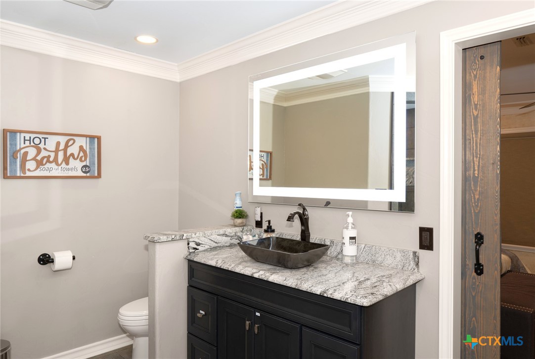 582 Cypress Valley Road Cuero, TX 77954 - Photo 36 of 36 a bathroom with a granite countertop sink a mirror and a toilet