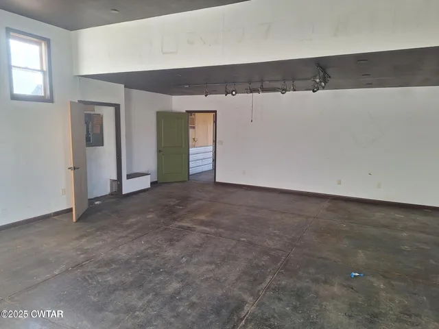 a view of a refrigerator in kitchen and an empty room