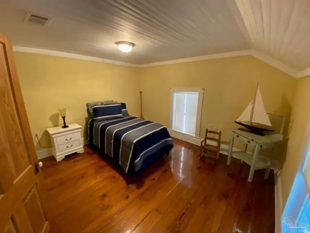 a bedroom with a bed and wooden floor