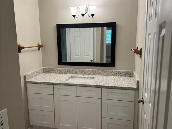 a bathroom with a granite countertop sink and a mirror