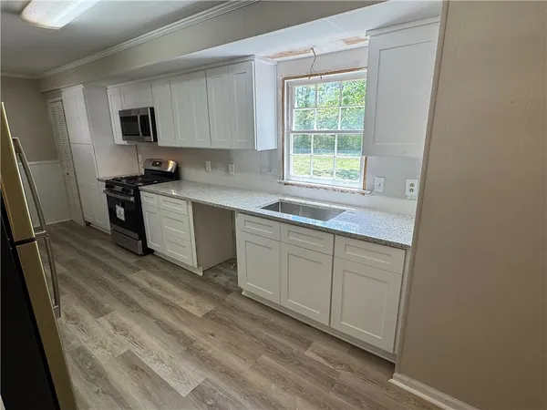 a kitchen with a sink cabinets appliances and a window