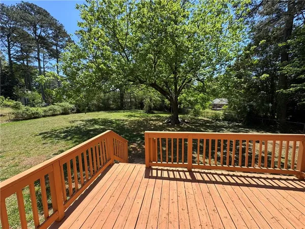 a view of wooden deck with a big yard and wooden fence