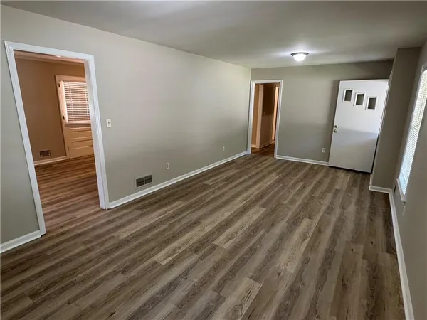 a view of an empty room with wooden floor and a window