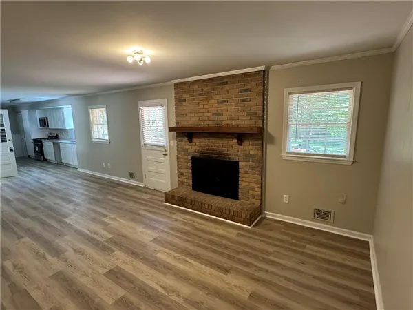 an empty room with wooden floor fireplace and windows