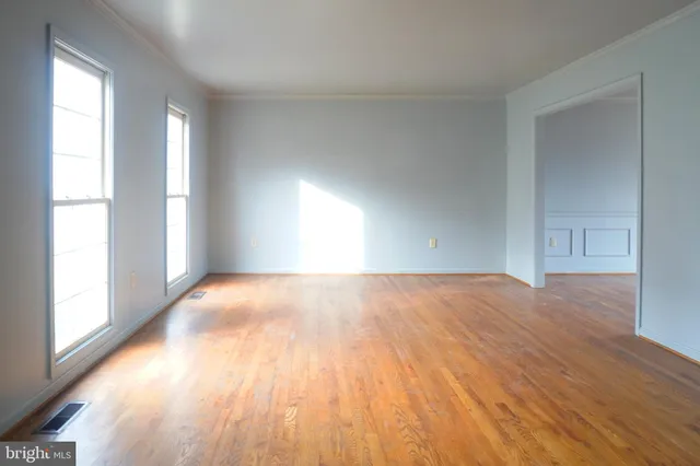 an empty room with wooden floor fireplace and windows