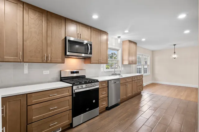 a kitchen with stainless steel appliances granite countertop wooden cabinets and a stove top oven