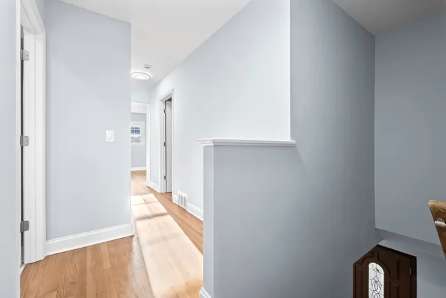 a view of a hallway with wooden floor and a bathroom