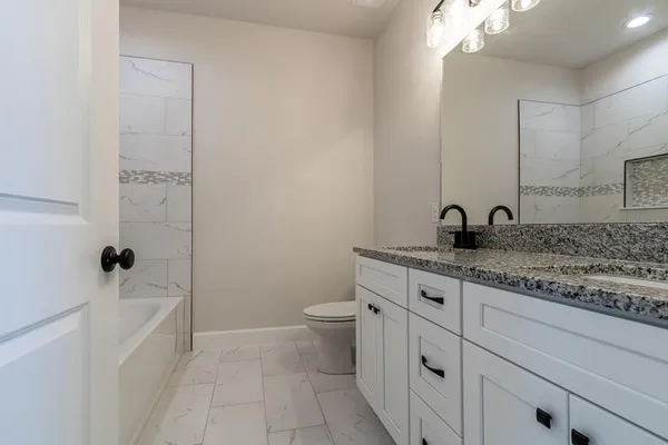 a bathroom with a granite countertop sink a toilet and shower