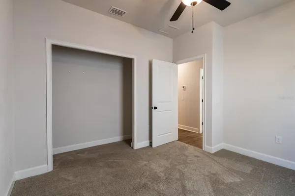an empty room with ceiling fan and window