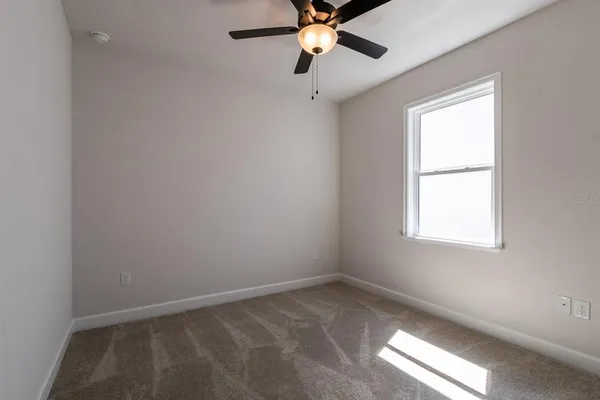 an empty room with a window and a fan