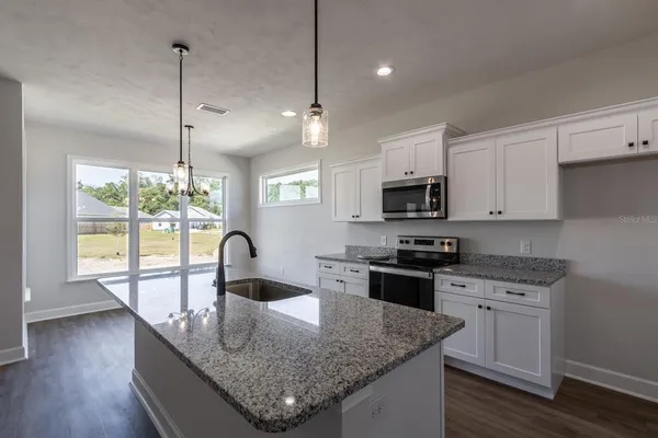 a kitchen with granite countertop stainless steel appliances a stove sink microwave and cabinets