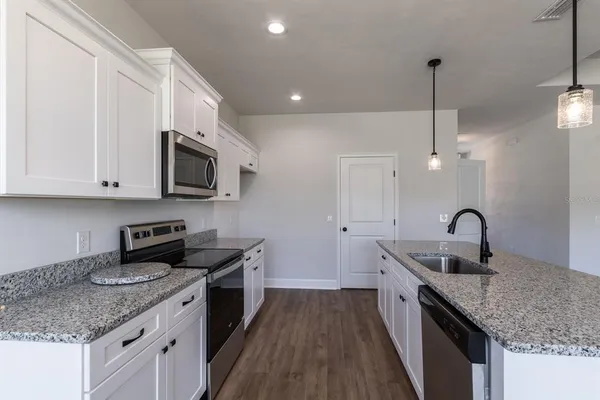 a kitchen with granite countertop a sink a counter space appliances and cabinets