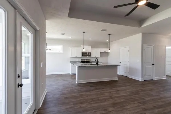 a large kitchen with a refrigerator and wooden floor