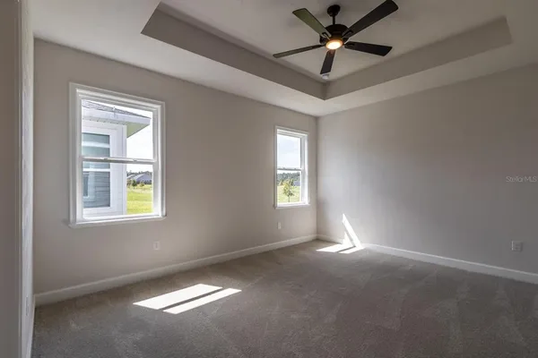 a view of an empty room with window and chandelier fan