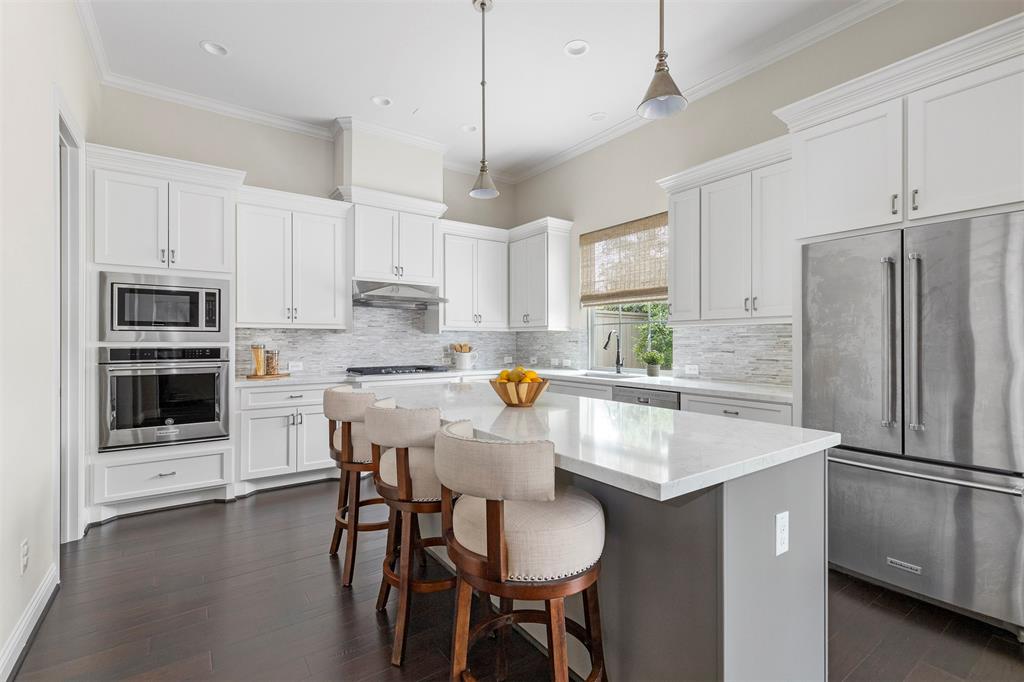a kitchen with stainless steel appliances a refrigerator a stove a white table and chairs