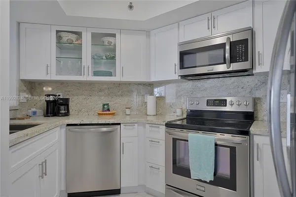 a kitchen with cabinets stainless steel appliances and wooden floor