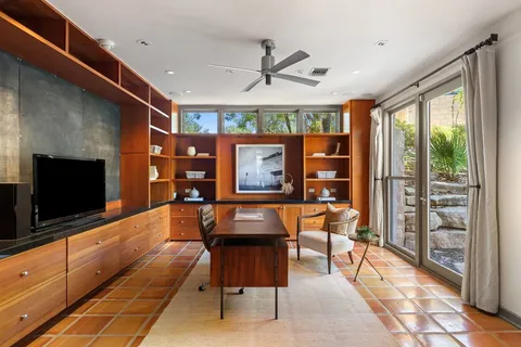 a living room with furniture a flat screen tv and a floor to ceiling window
